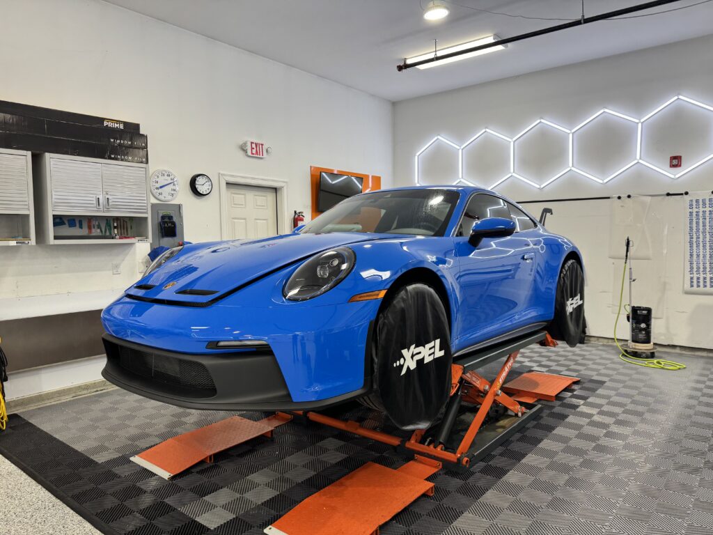 Paint protection film maine on a porsche 911 that is lifted off the ground with orange lifts